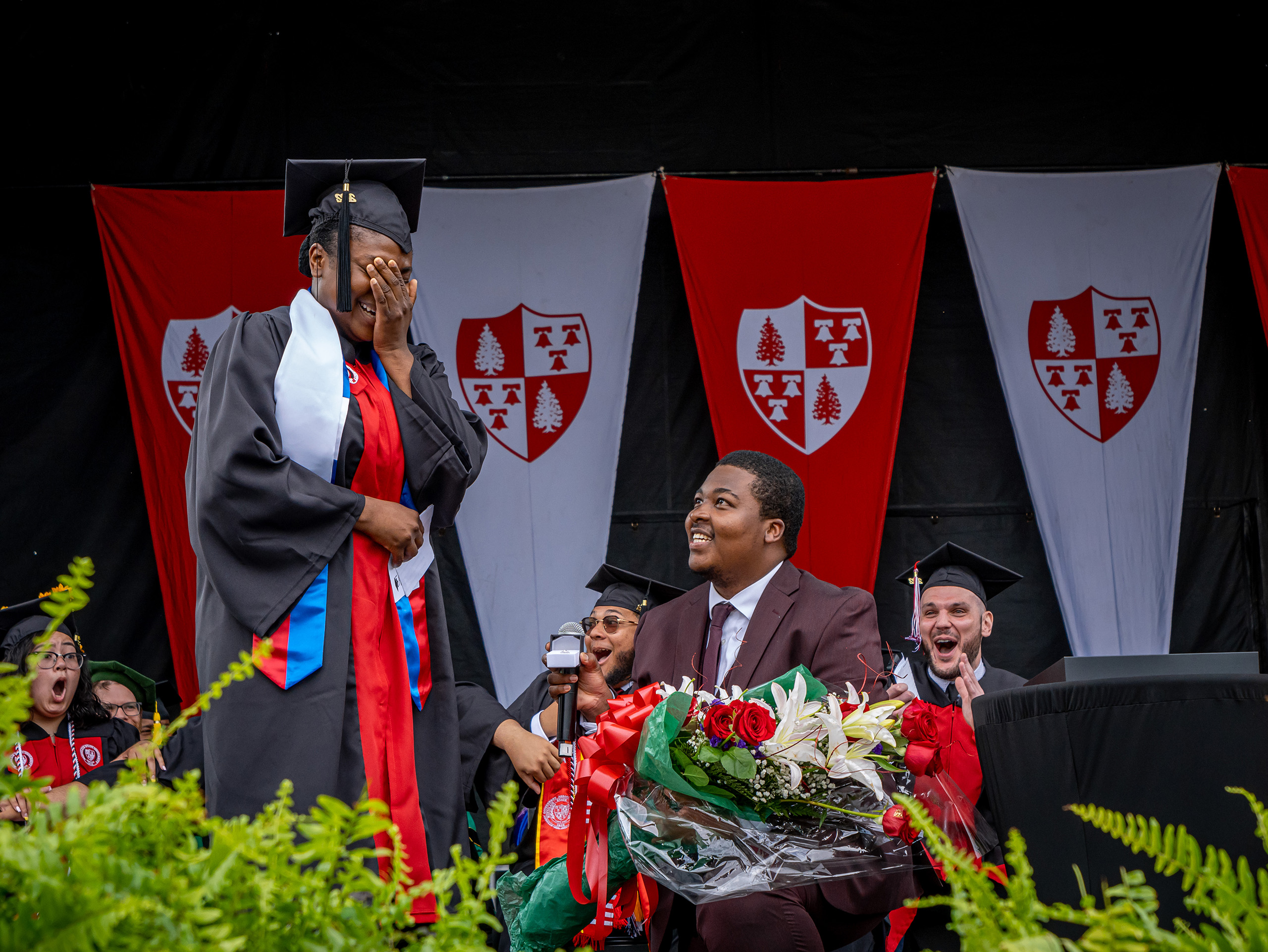 Man proposing to woman in cap and gown on stage