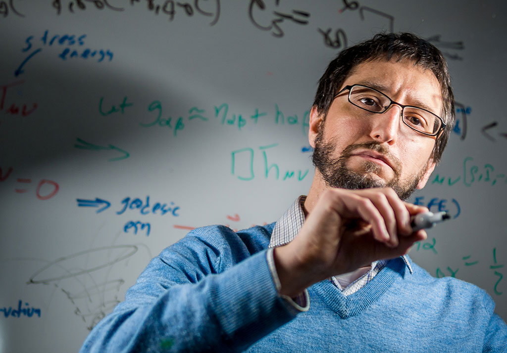 Photo of Marc Favata writing equations on glass.