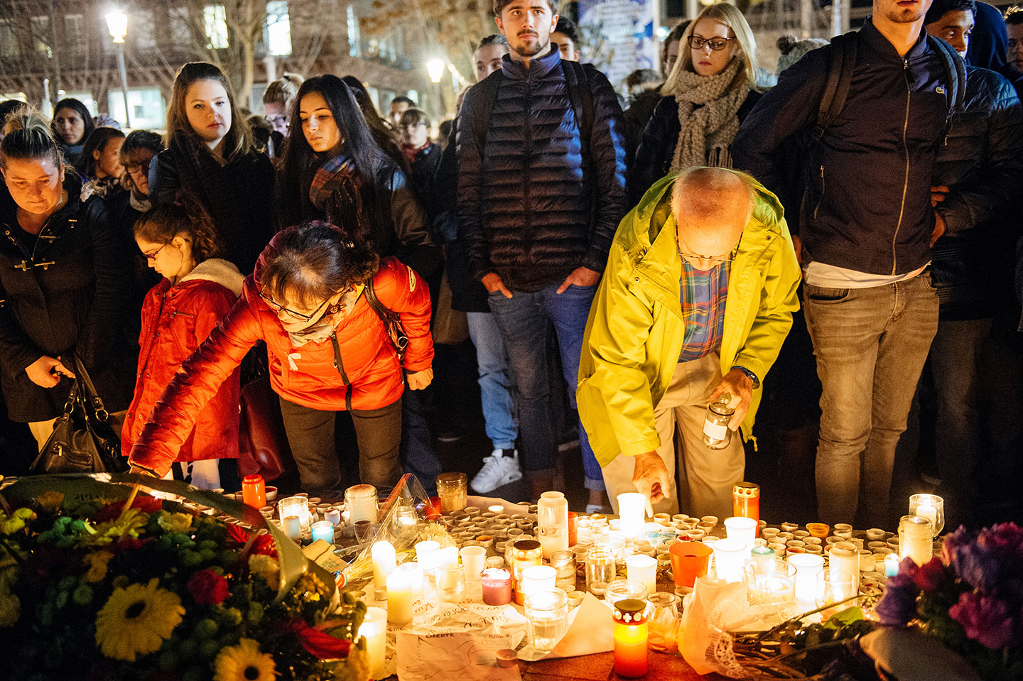 Mourners place candles at a memorial for victims of the 2015 Paris terror attacks.