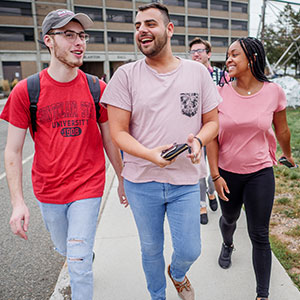 Three Montclair State University students walking and smiling.