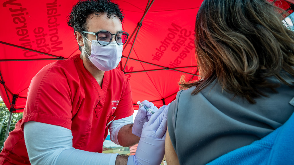 Nursing student Jhoniel Santiago administers a flu shot at an outdoor flu clinic.