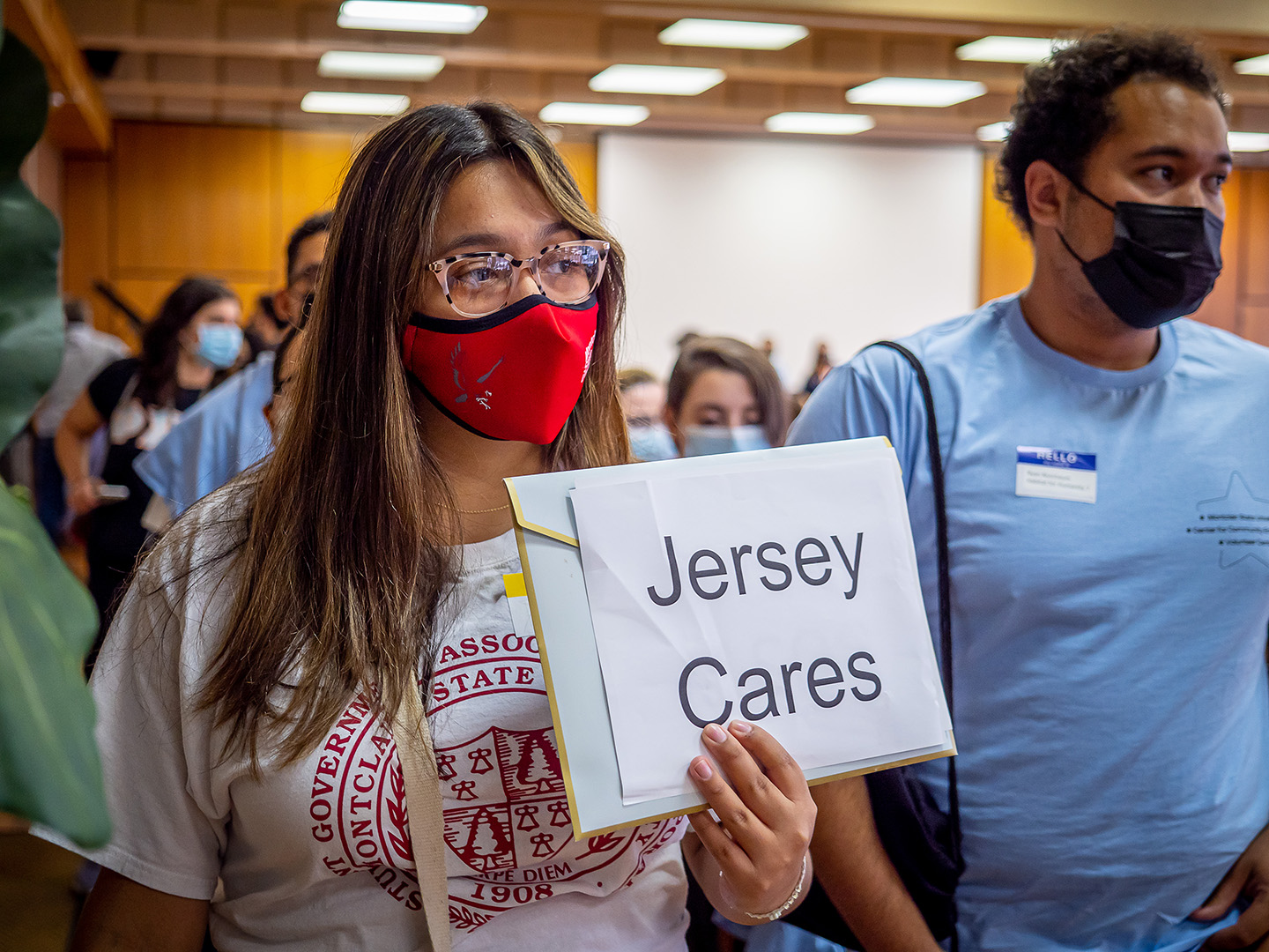 student wearing mask holding "Jersey Cares" sign