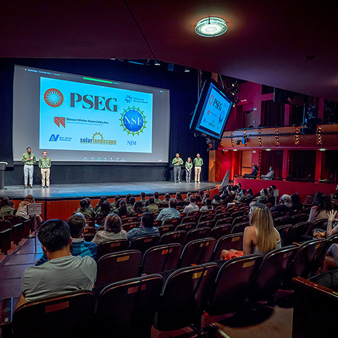 Members of the PSEG Institute on stage in front of a presentation screen
