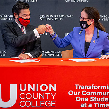 Montclair President Jonathan Koppell and Union President Margaret M. McMenamin do a "fist-bump" at a table after signing an agreement