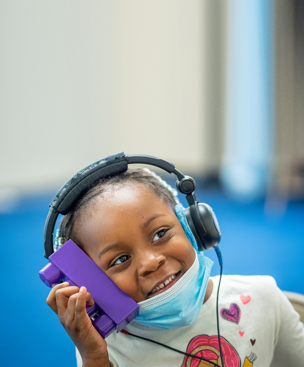 young child holding block while wearing headphones