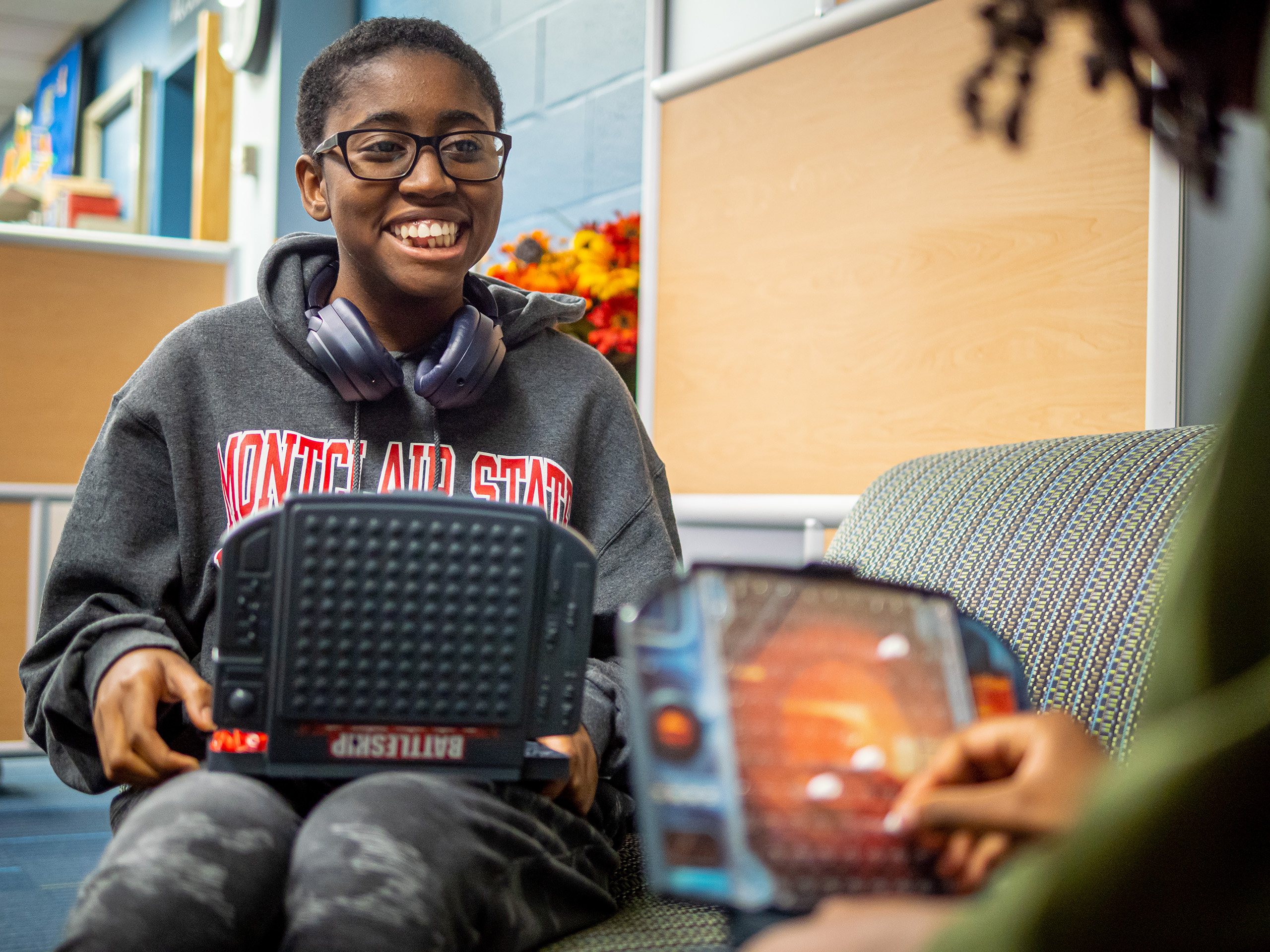 Student smiling with battleship game on lap