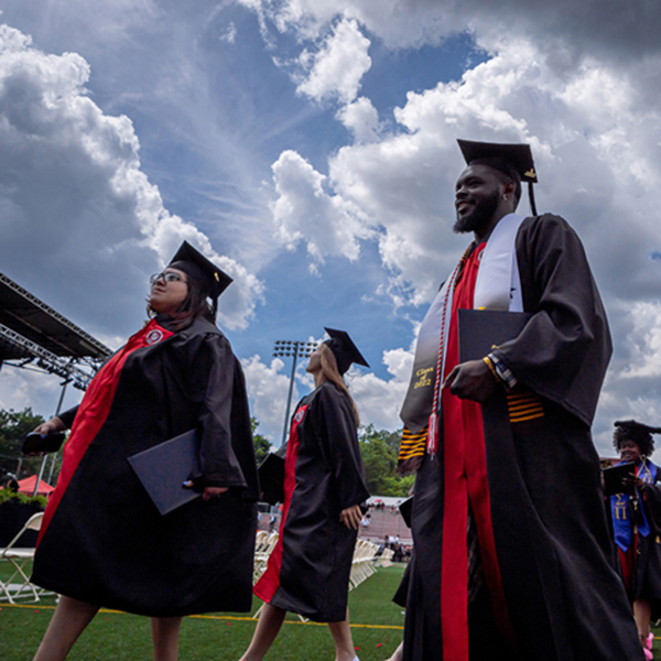 graduates walking on campus in caps and gowns