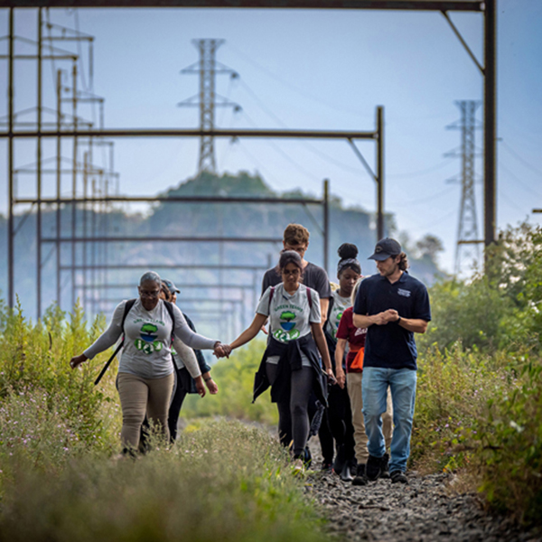 Group of people walking along overgrown railroad tracks