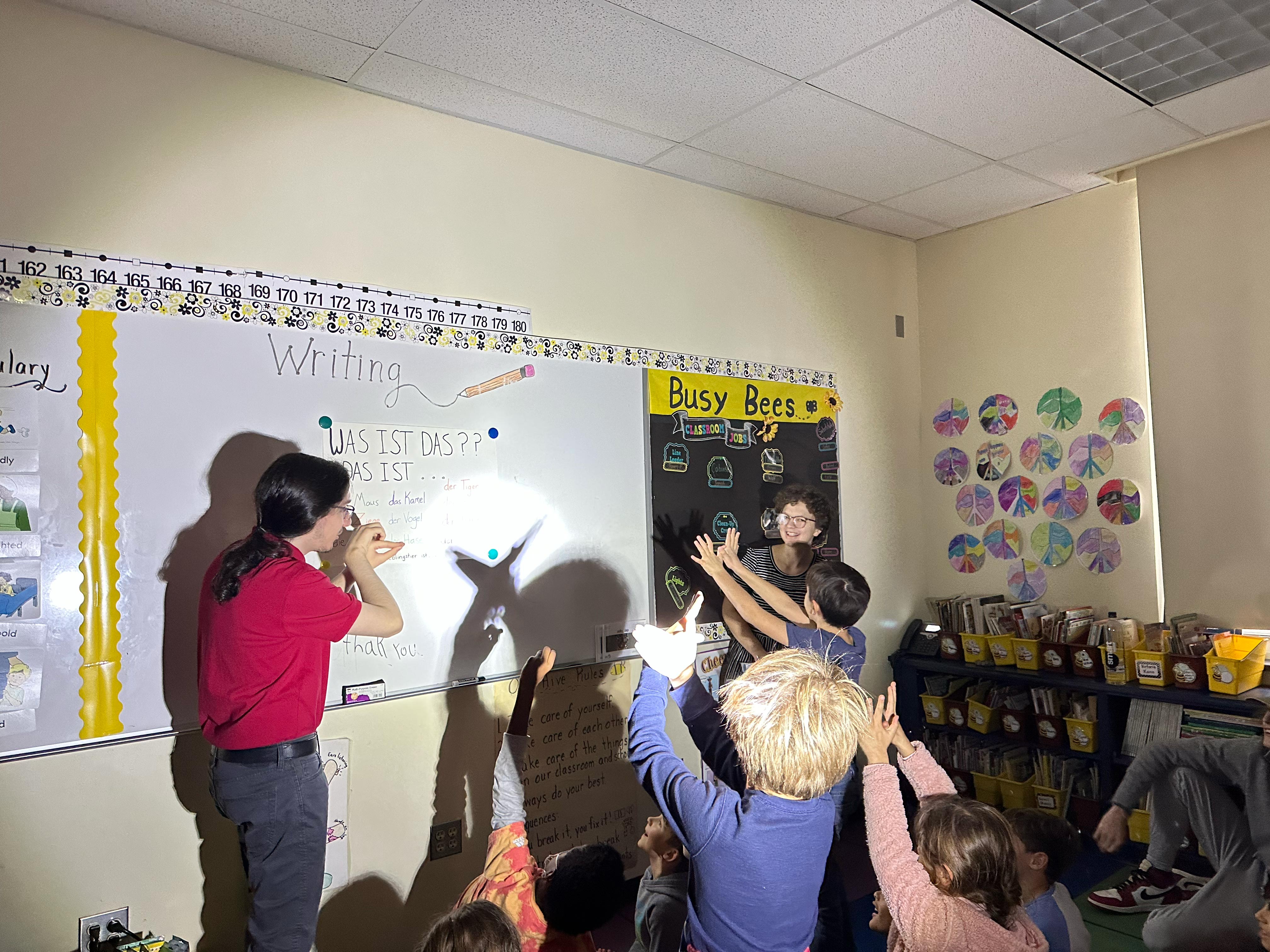 German SPARK Lab students and elementary students making shadow puppets on board