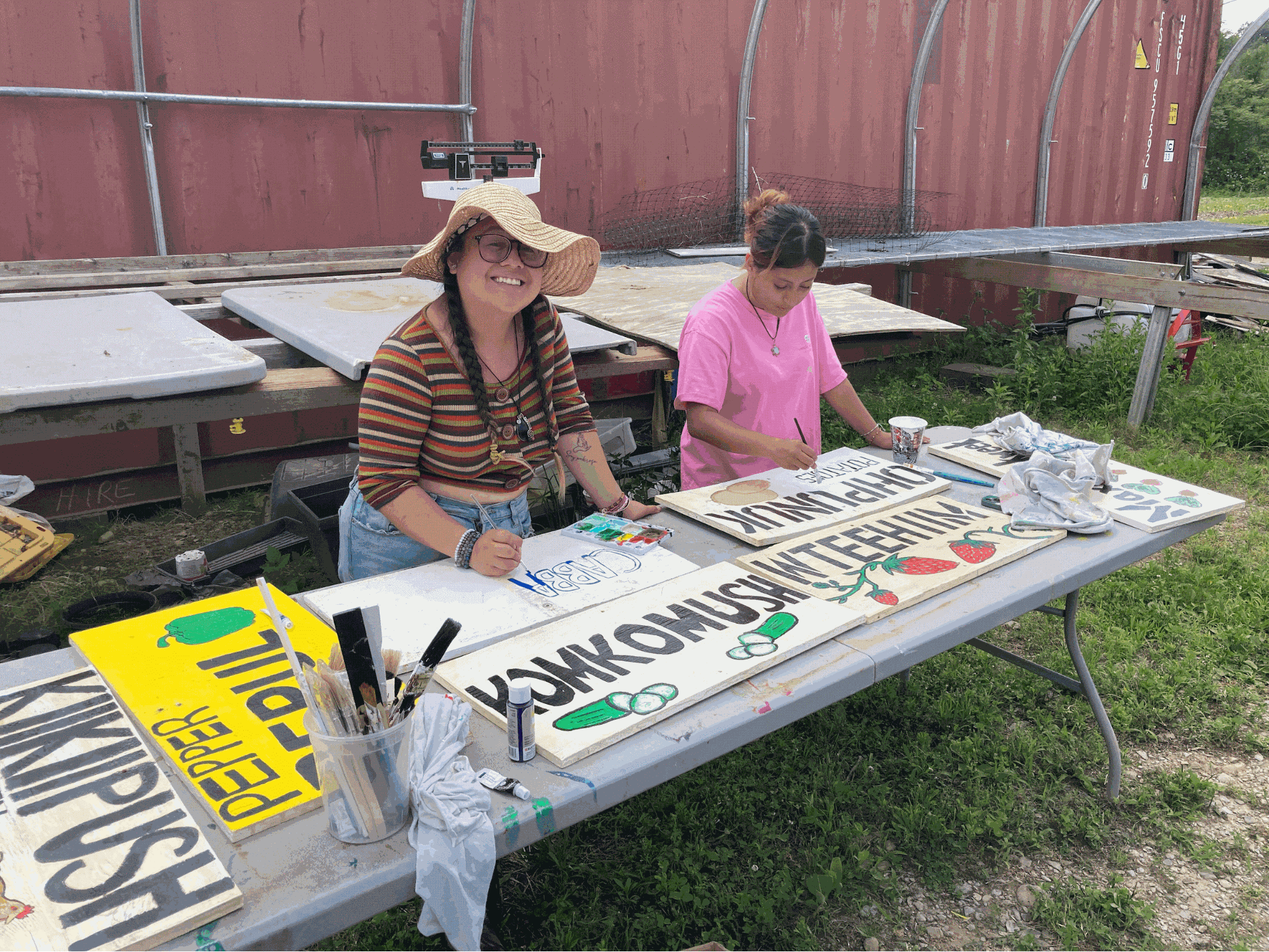 student smiles while painting a sign
