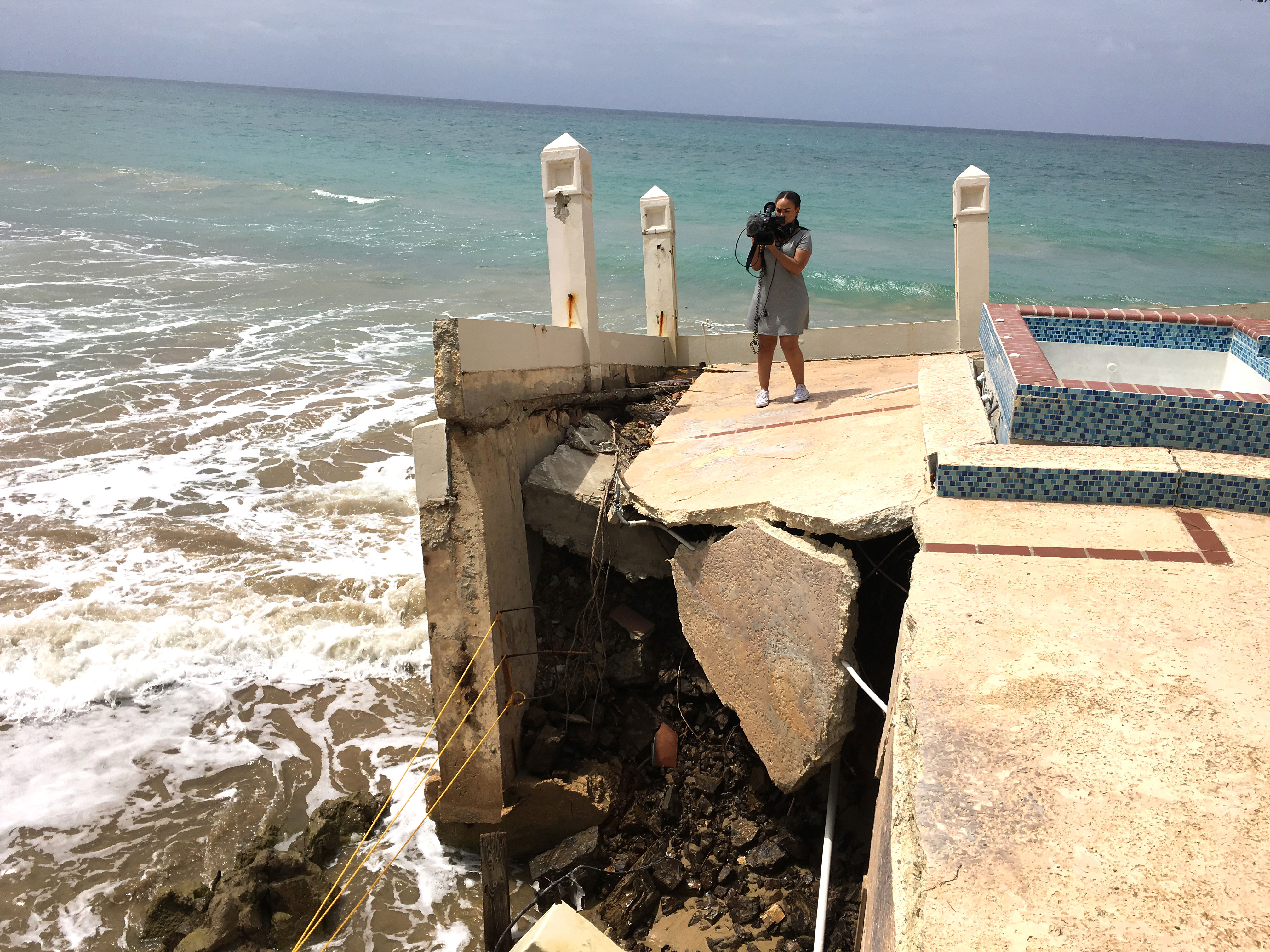 Female student in Puerto Rico holding camera in front of beach