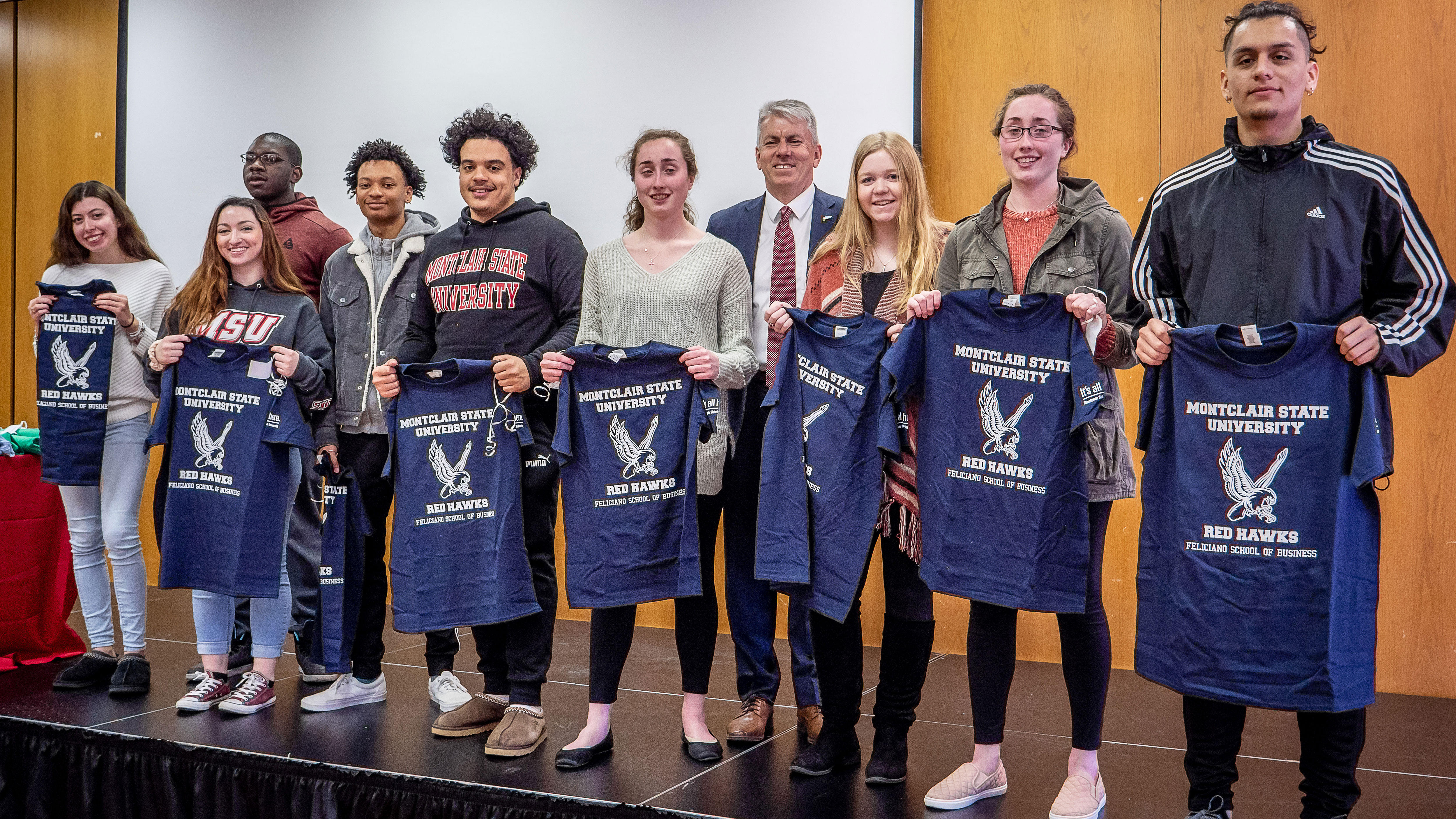 Feliciano School of Business students holding navy blue shirts