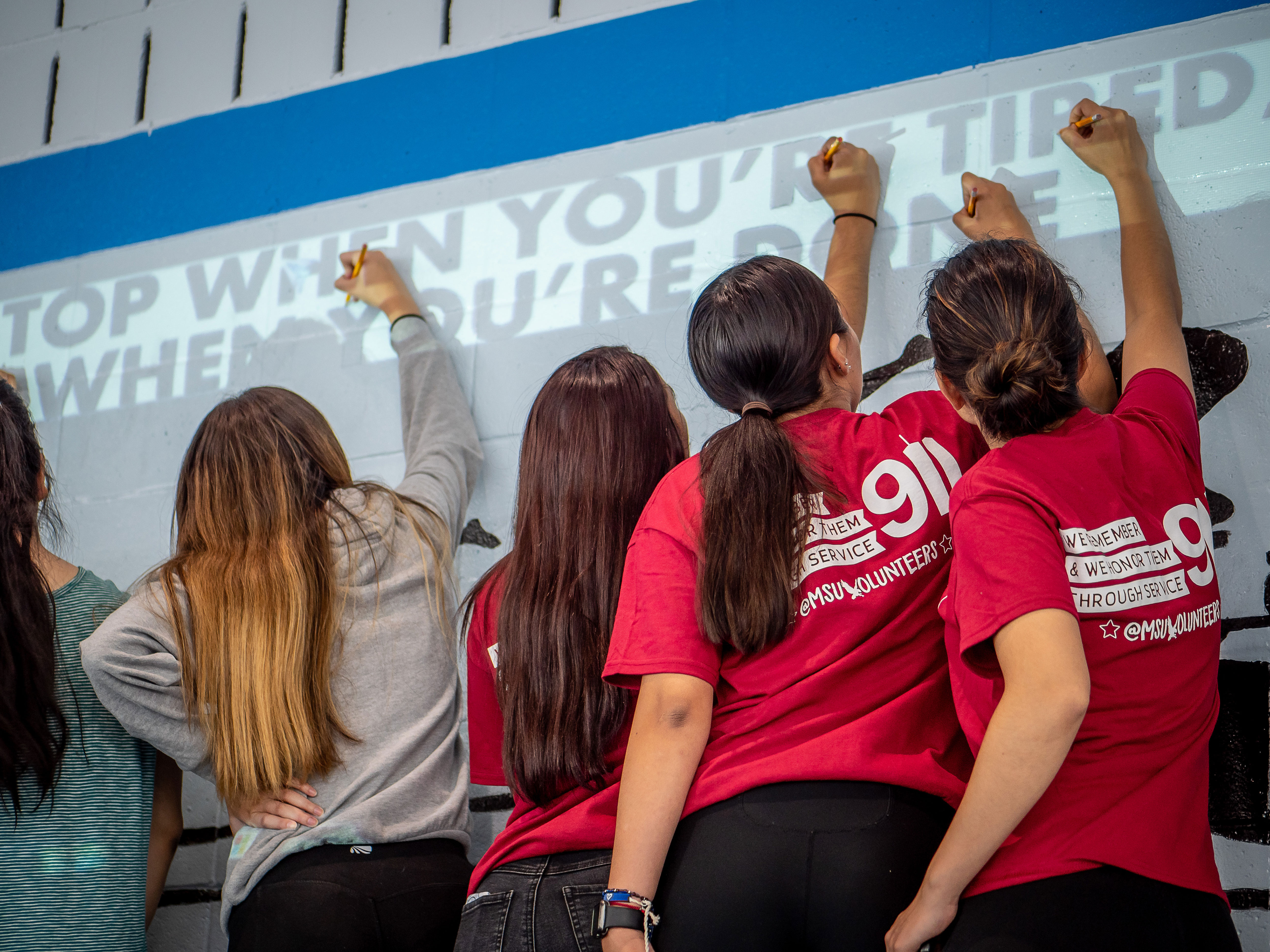 Montclair State volunteers stencil lettering during National Day of Service.