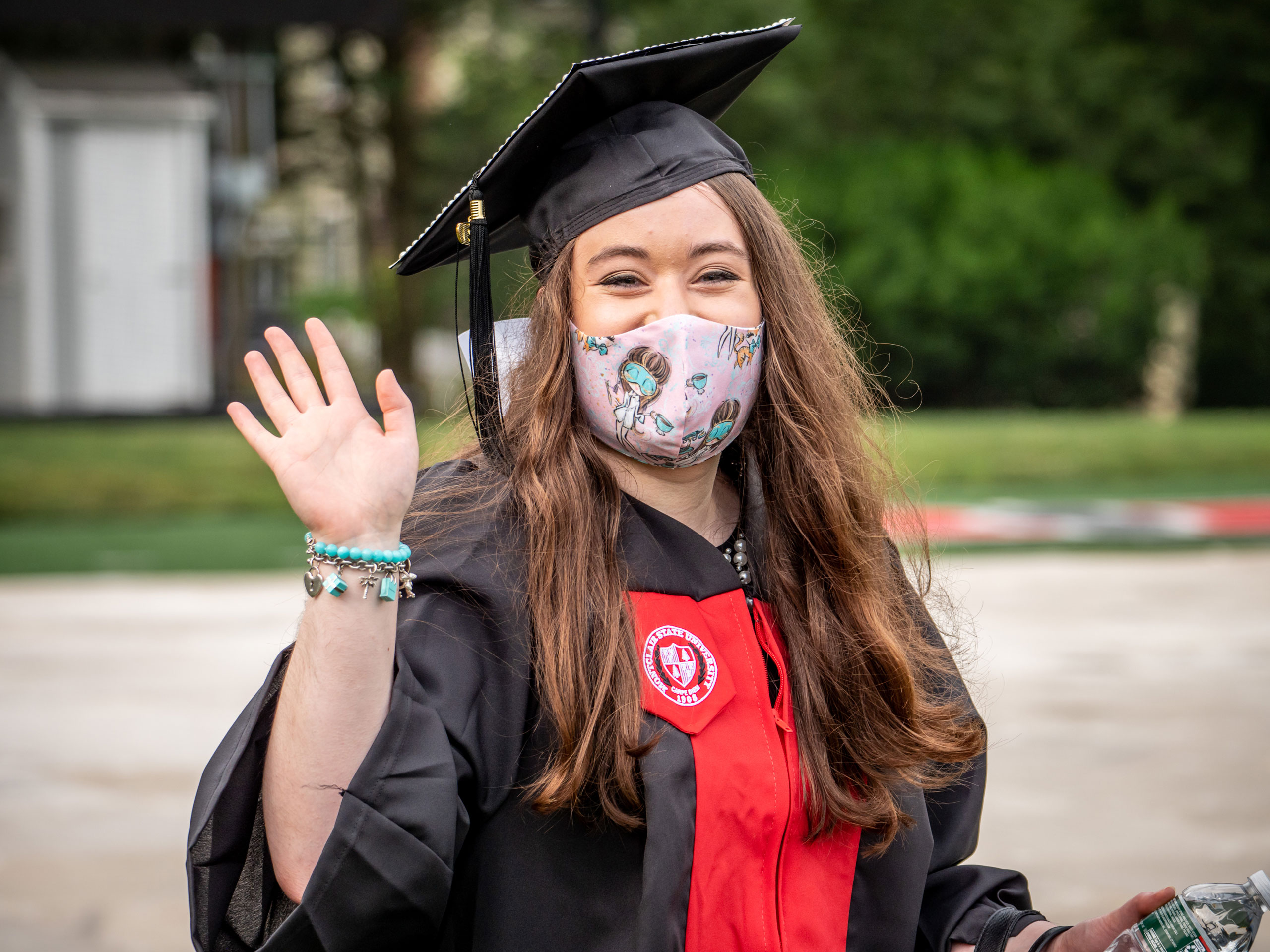 student waving toward camera an smiling