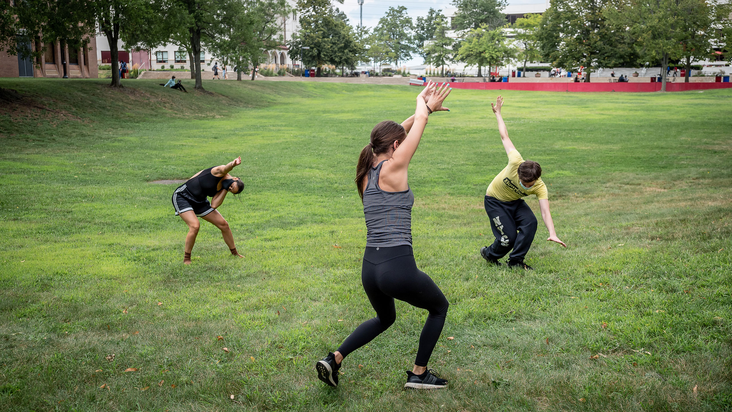 Students stand distanced from each other on the quad practicing tai chi