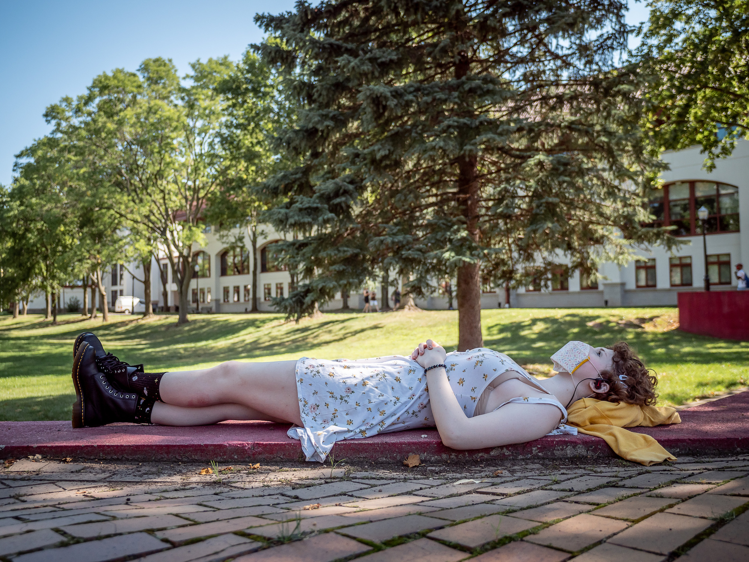 A student lying down under trees on a college campus