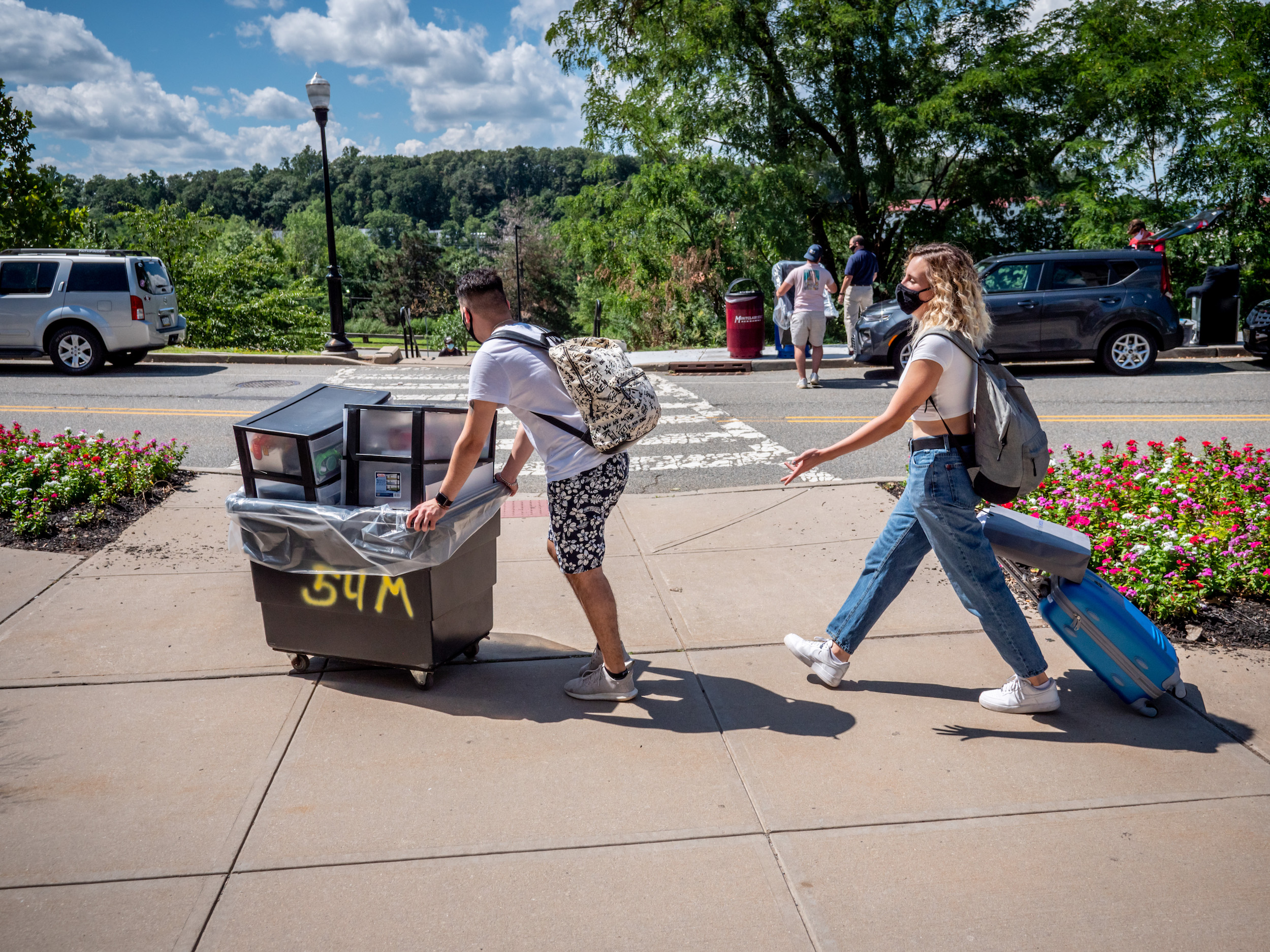 Students outside moving their belongings across a parking lot on campus