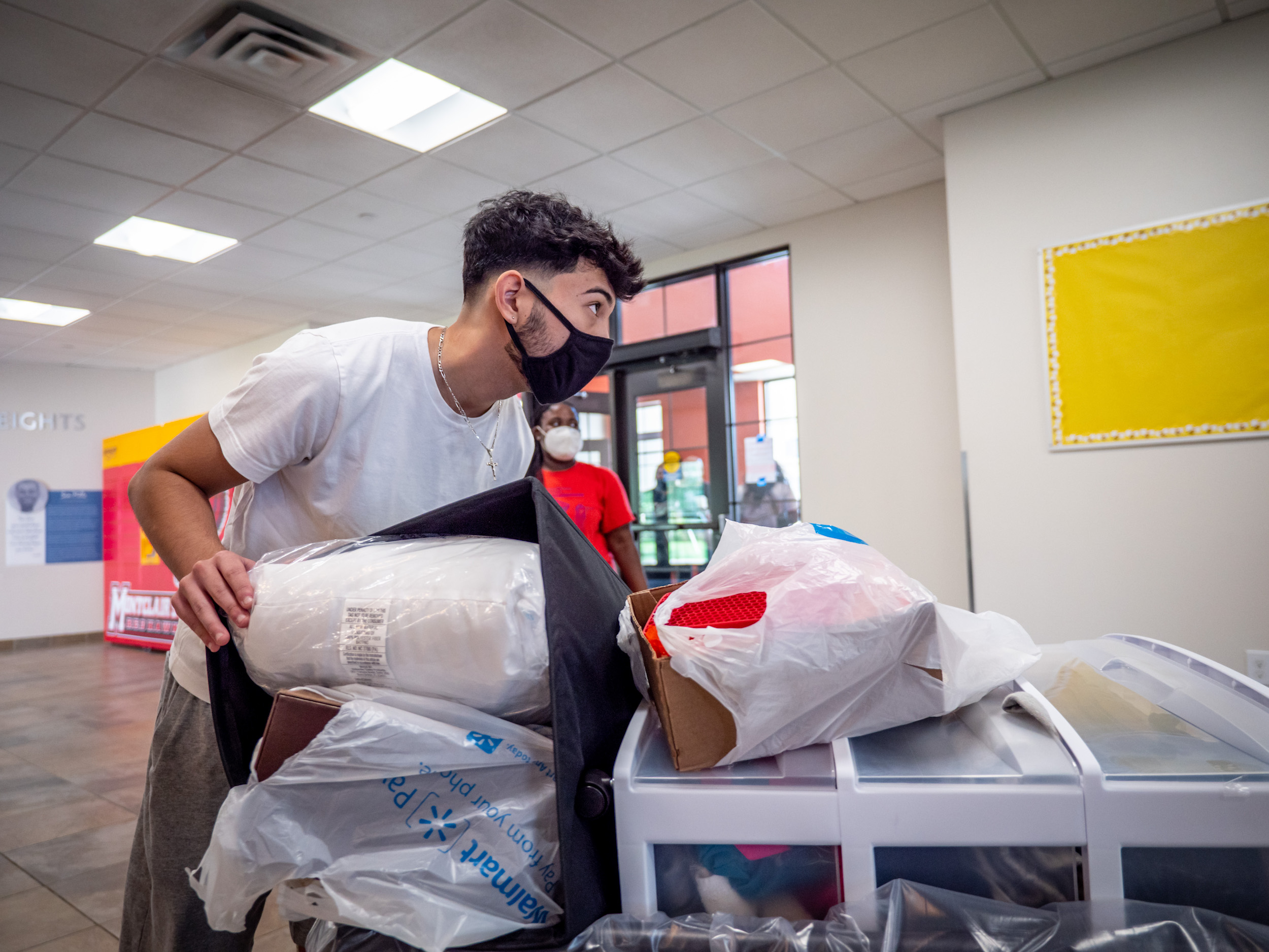 A student pushing his belongings on a cart through a residence hall on campus