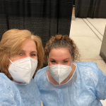 Associate Professors Marybeth Duffy and Courtney Reinisch in scrubs and masks at a vaccine center