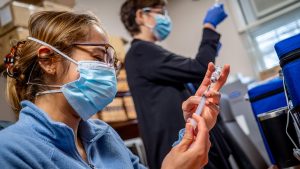 nurse drawing dose into syringe from vial