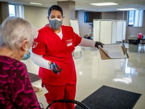 Nurse in facitlity with clipboard directing a senior citizen