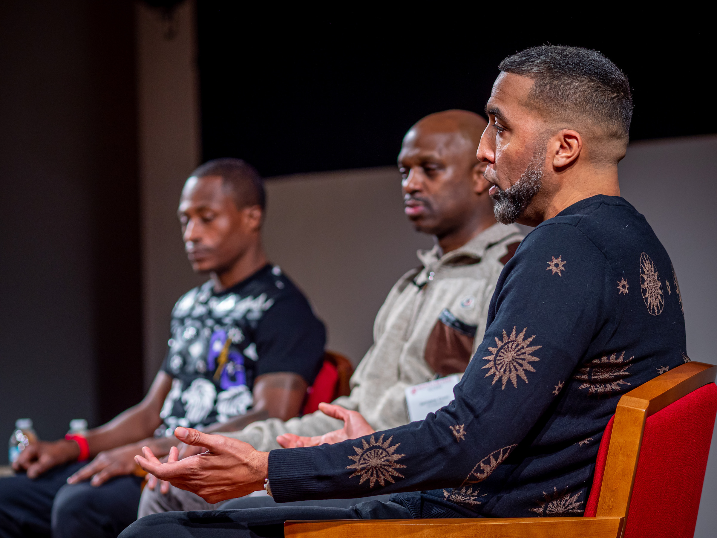 TDanny Reyes, foreground, speaks while Jarmaine Grant, center, and Rayshawn Brown listen.