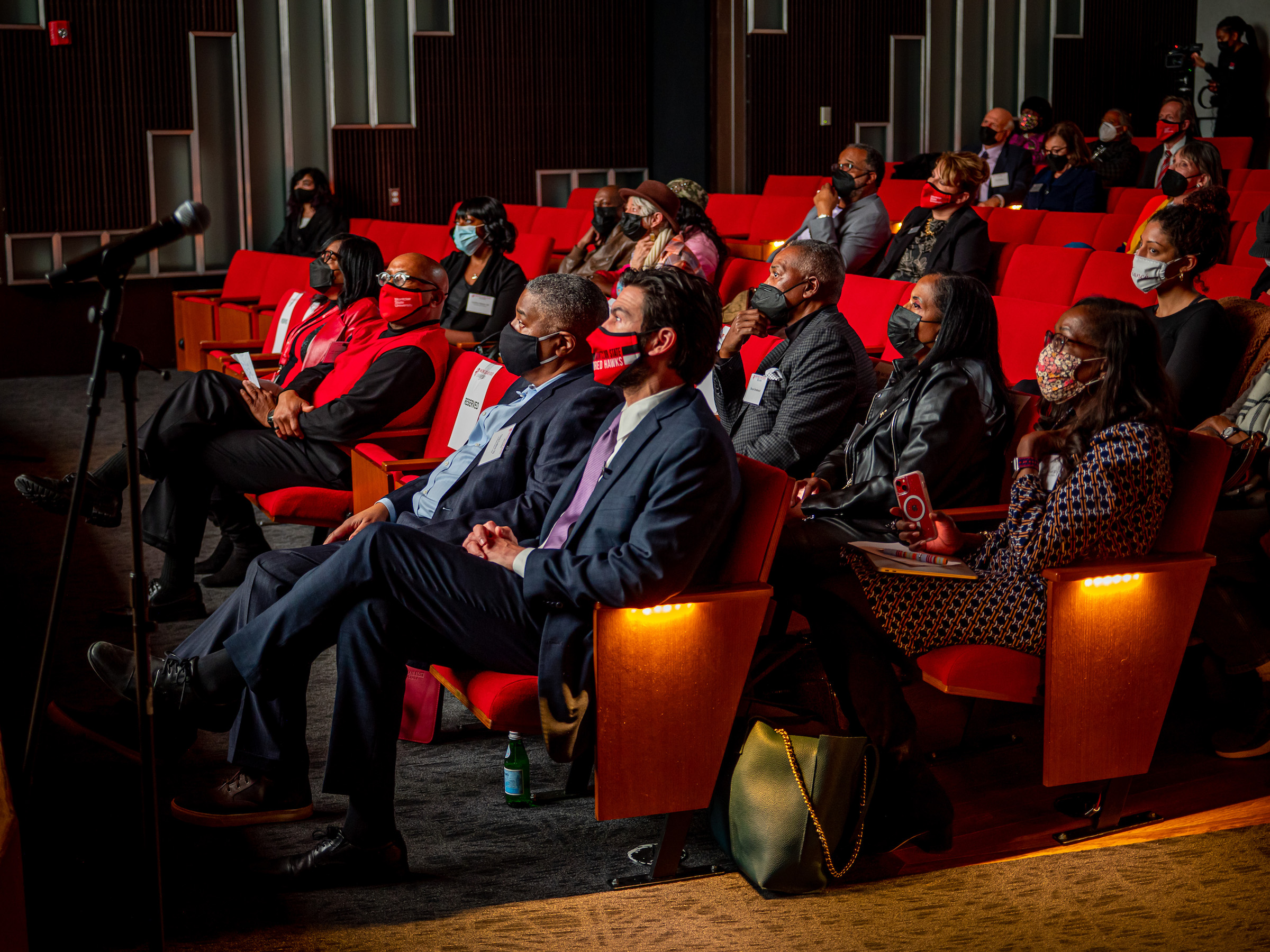 Audience members, including President Jonathan Koppell and Montclair State Foundation Board Chairman Greg Collins in the front row, listen to the story of the Jersey Four. 