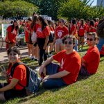 Students sitting on grass in red shirts
