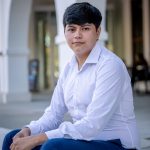 student seated on steps in front of arches