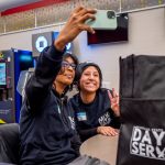 Two students pose and take a self-portrait with a phone.