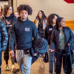 A group of students walk through a building lobby.