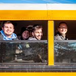 Five students look out school bus windows.