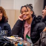 Three students sit at a table talking.