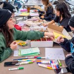 Students sit at a table writing.