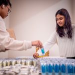 Two students place toothpaste tubes in bags.