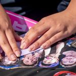 A close view of hands as a student folds a piece of paper with photos of a Korean pop group.