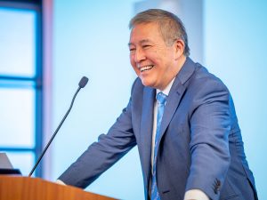 Junius Gonzales stands at a lectern, smiling.