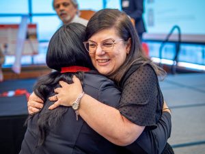 A woman hugs a student after presenting her with a medallion.