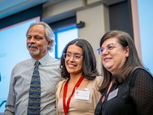 A man and a woman stand on either side of a student.