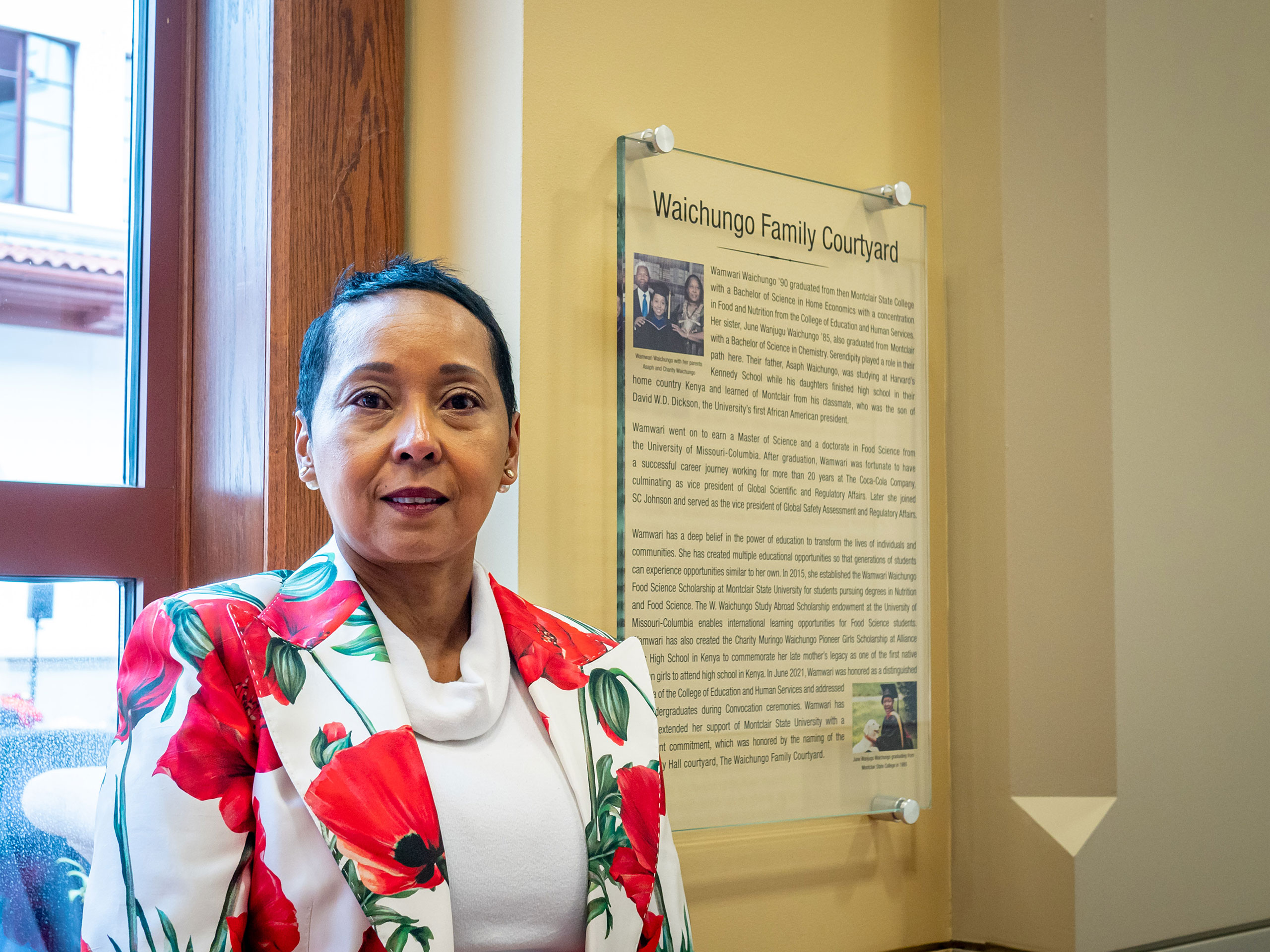 A woman stands in front of a plaque.