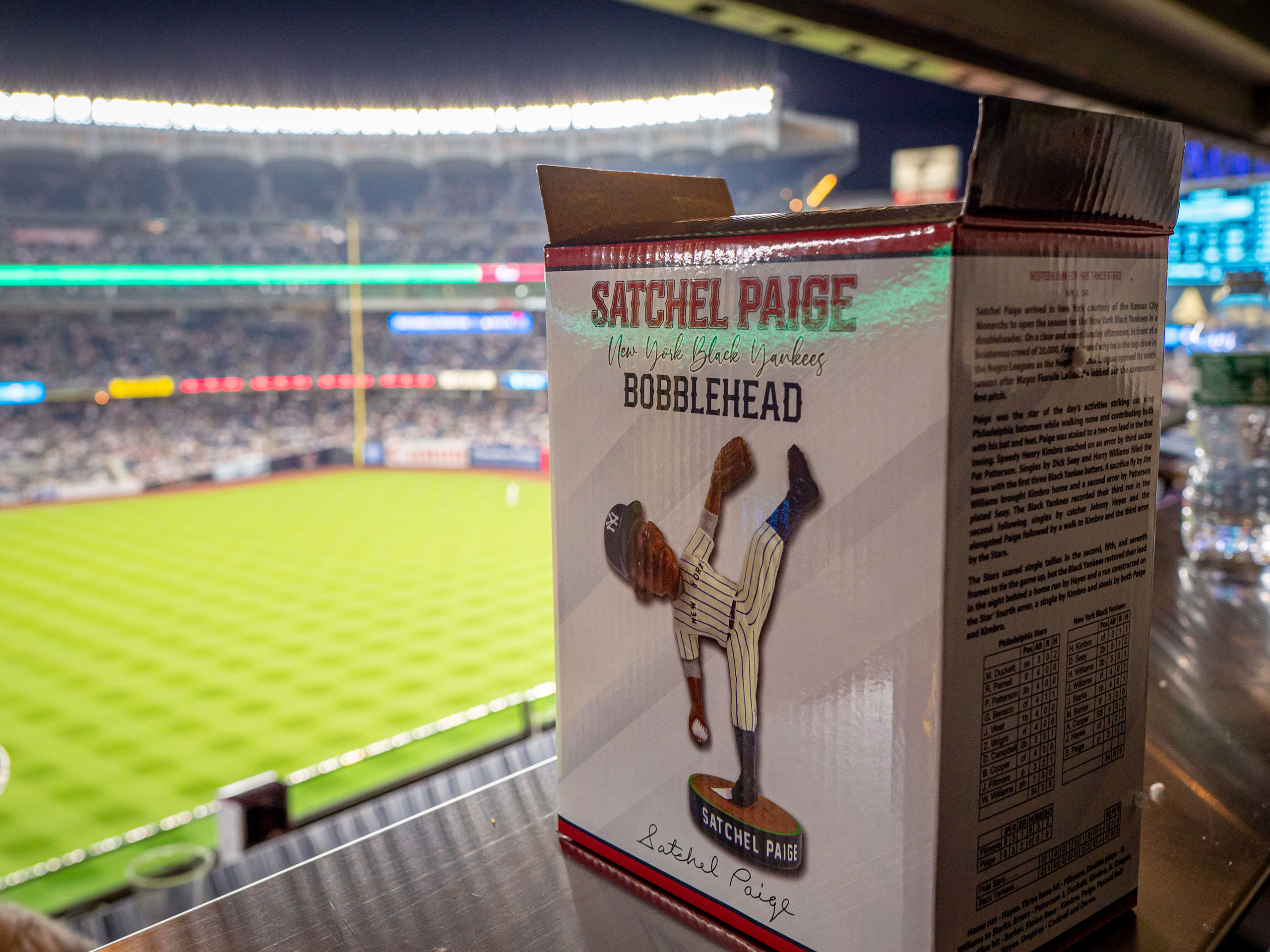 A box with a Satchel Paige bobblehead with a baseball field in the background.