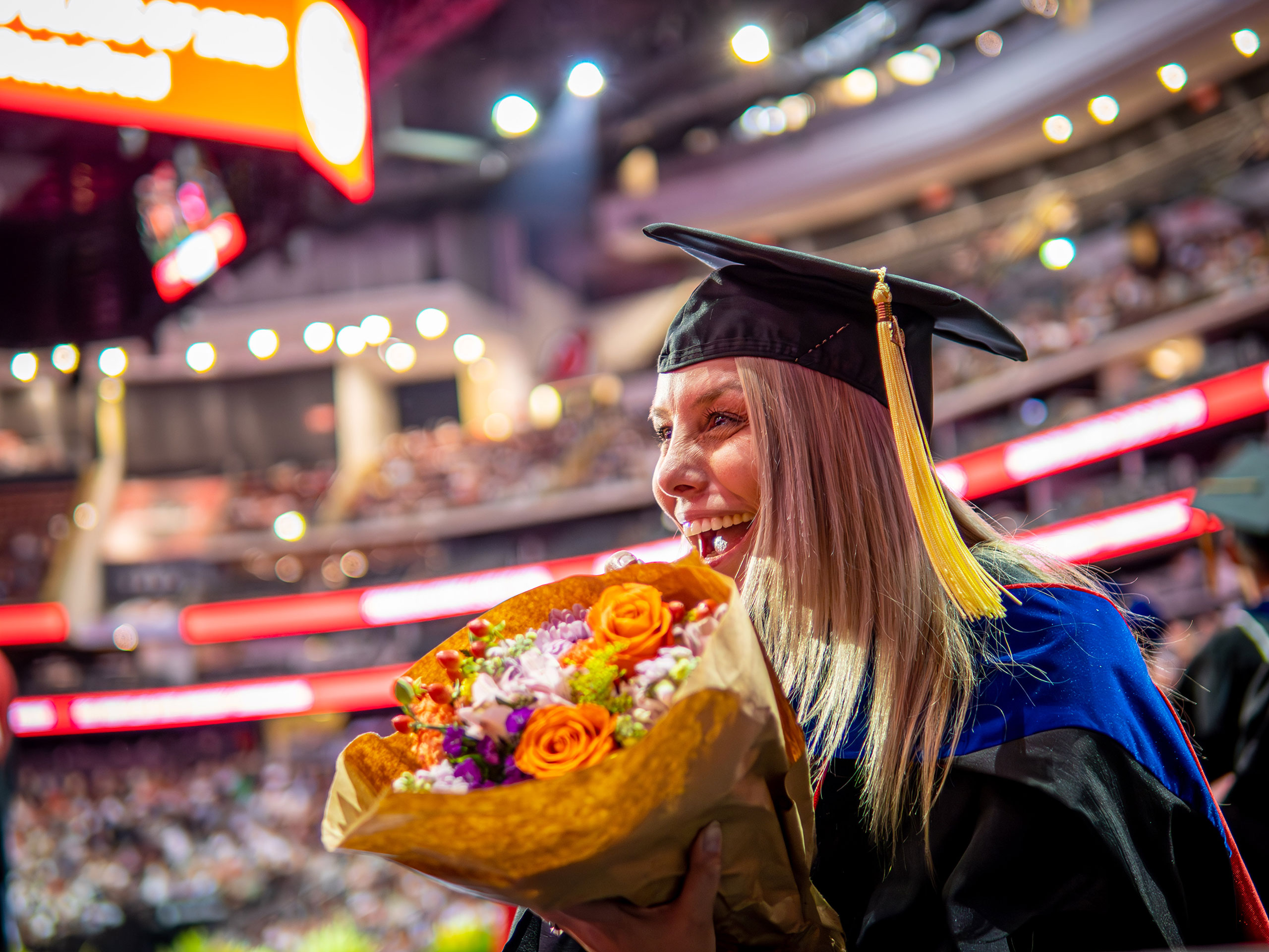 Graduate on stage holding a bouquet of flowers
