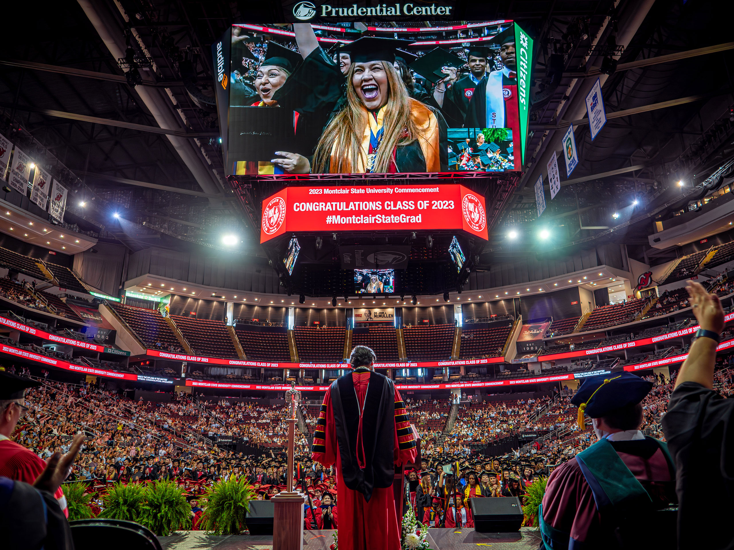 President Koppell on stage with the Prudential Center jumbotron above him showing gradutes in the crowd