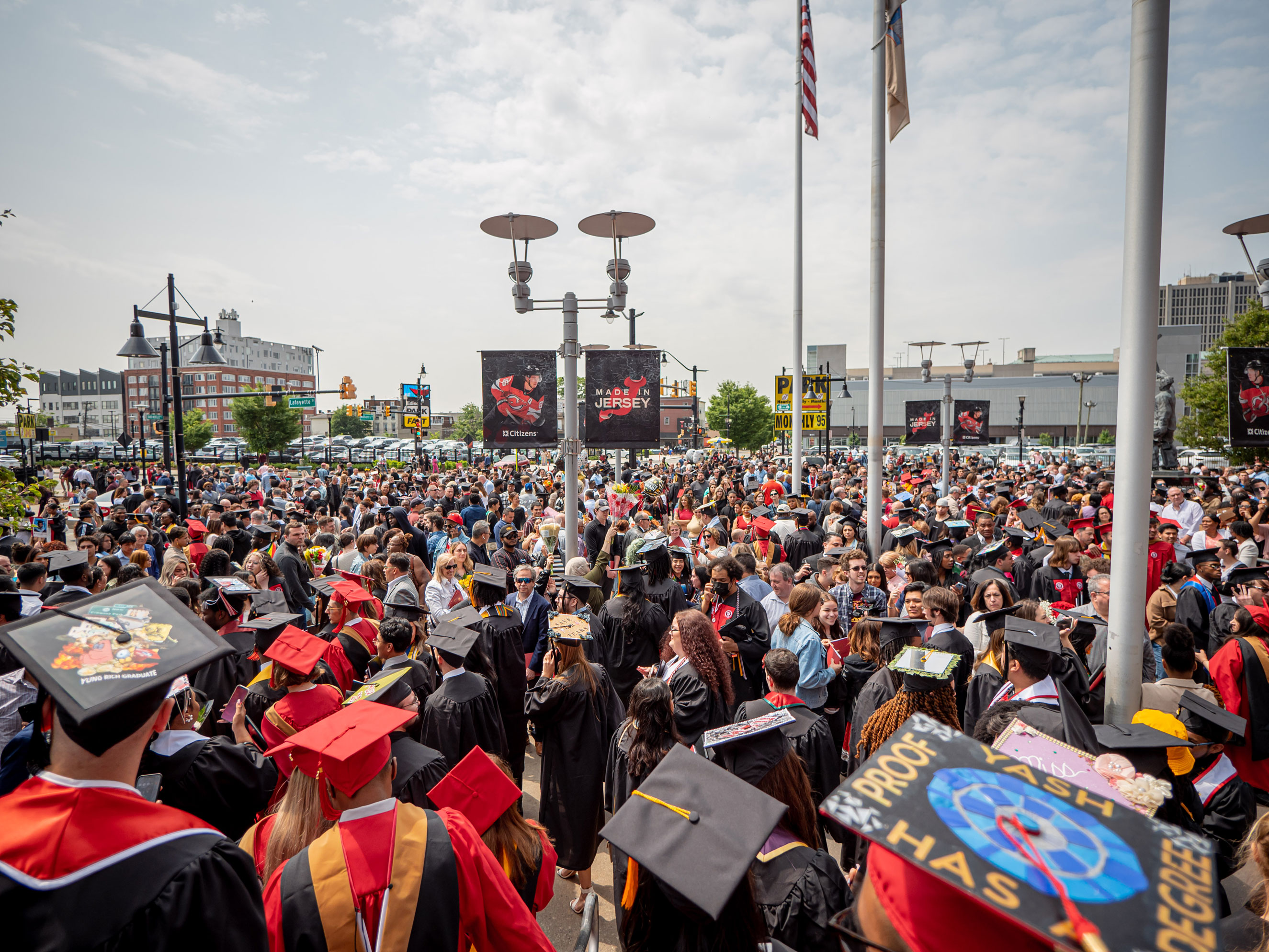 hundreds of graduating students in commencement attire gather outside arena
