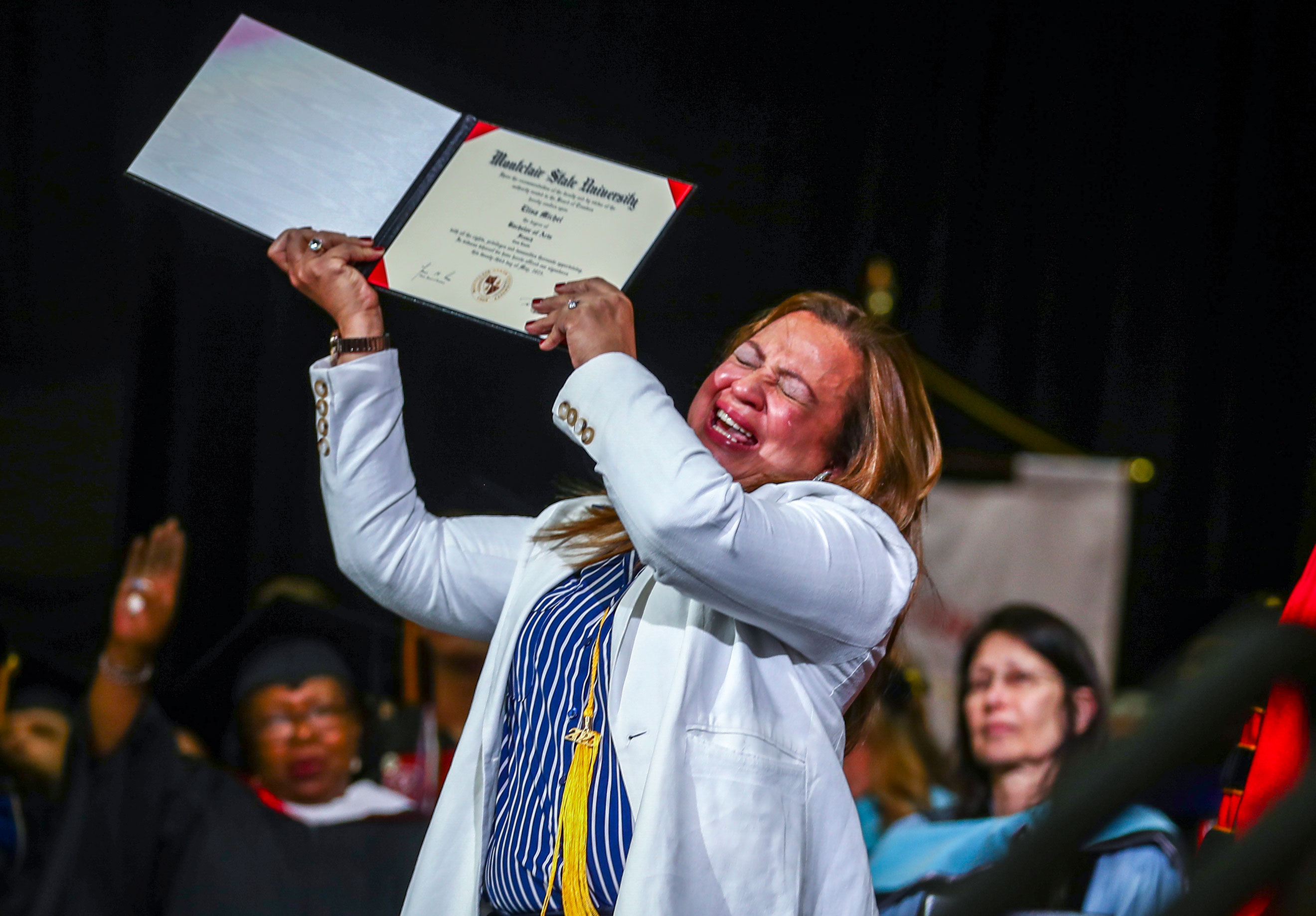 Grieving mother holds up daughter's posthumous college diploma.