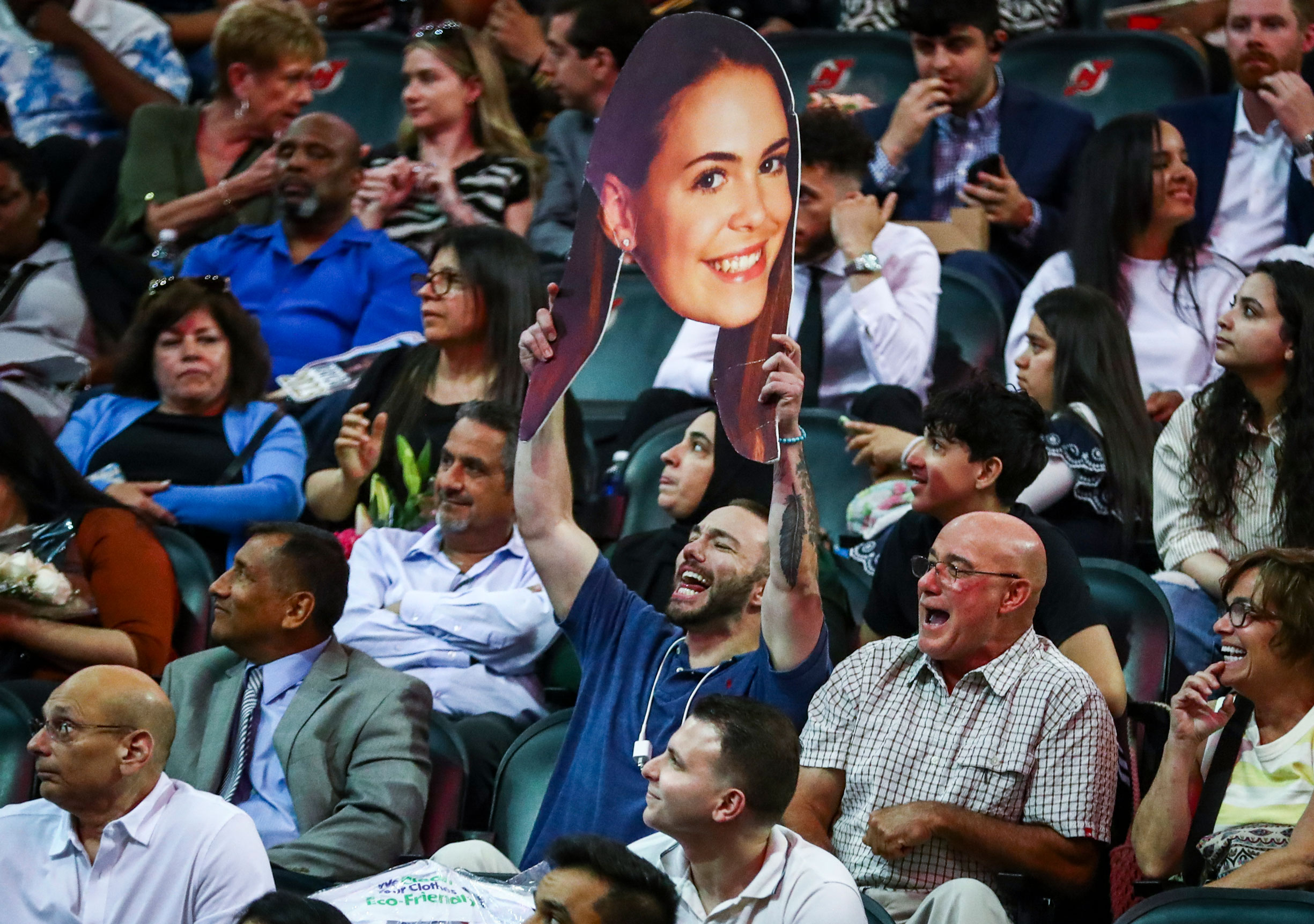 man holding giant cardboard head cutout featuring graduating student's photo