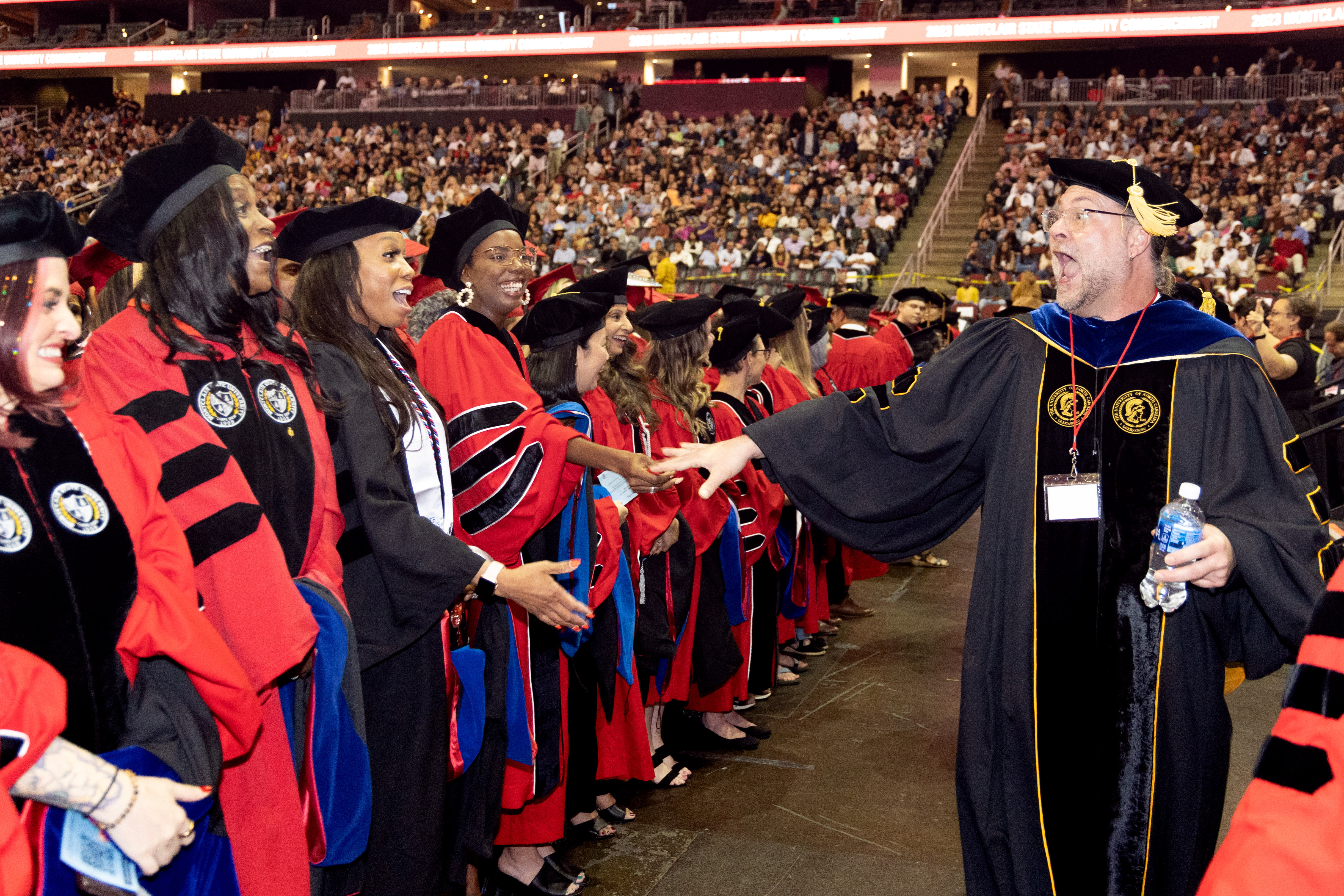 students and faculty joyfully greeting each other at commencement
