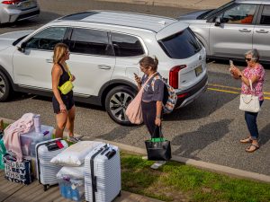 A woman takes a photo of a student and parent as they prepare to move into a dorm.