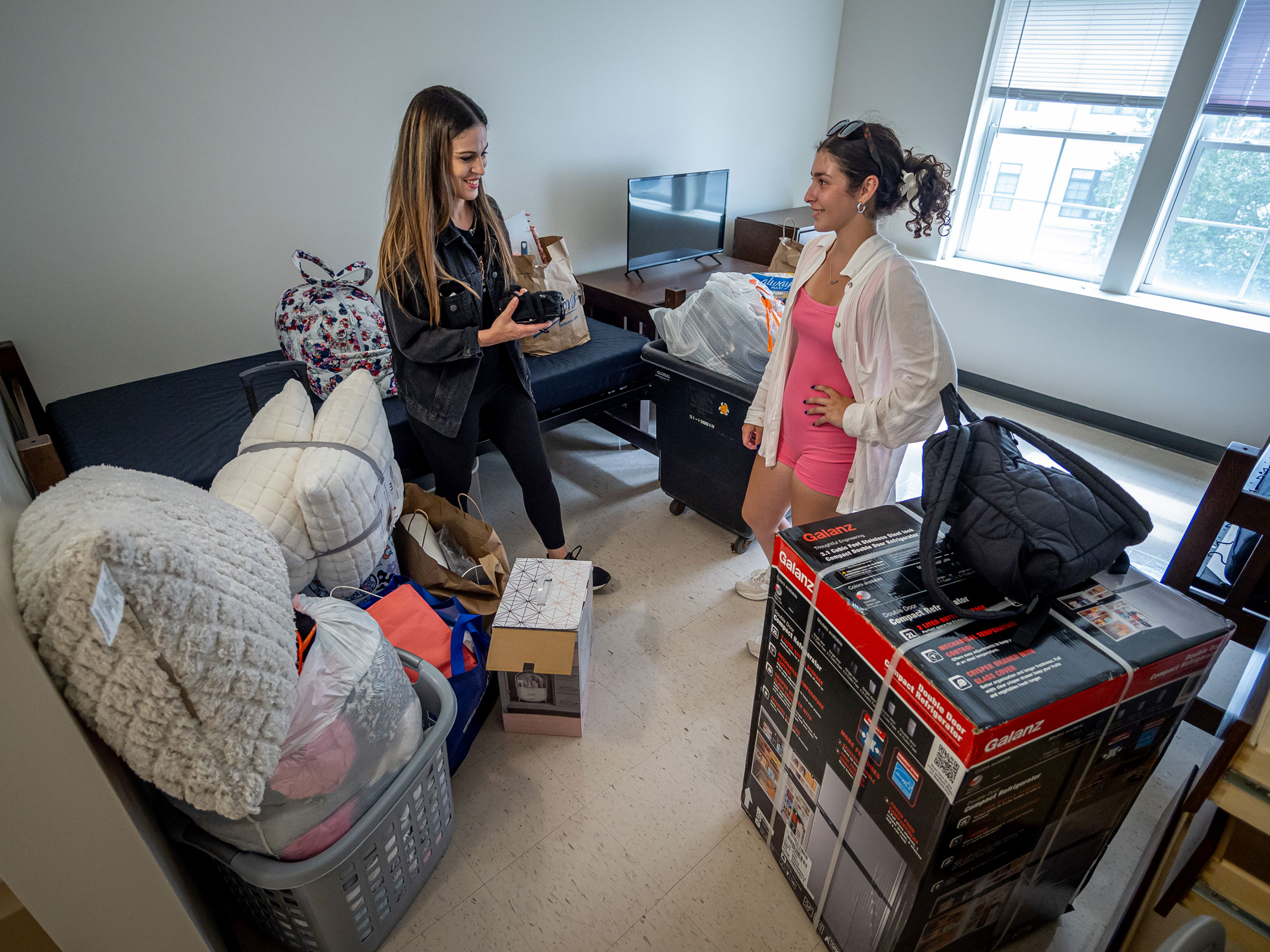 A mom and daughter in a room surrounded by belongings.