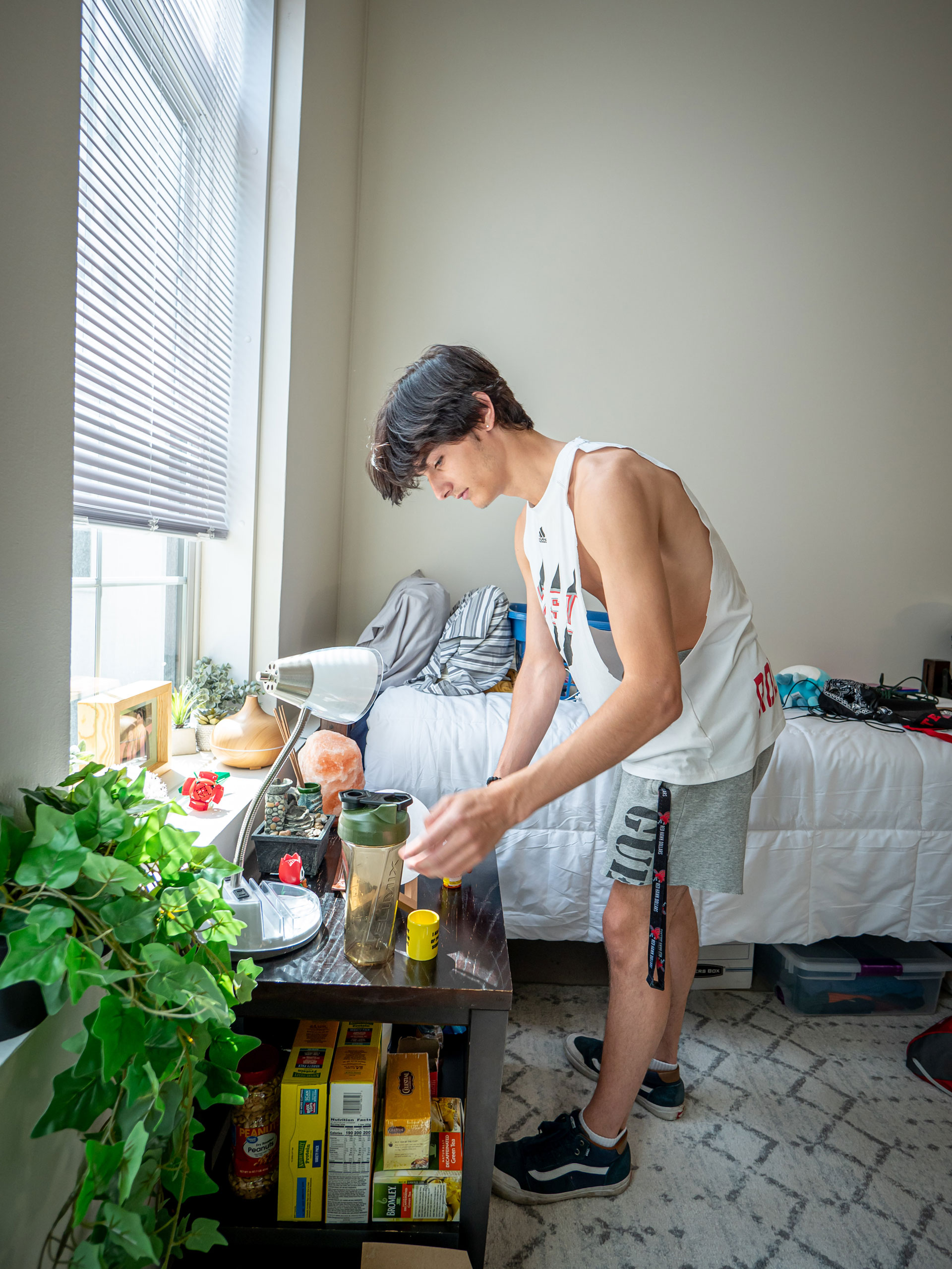 A young man sets up his dorm room.